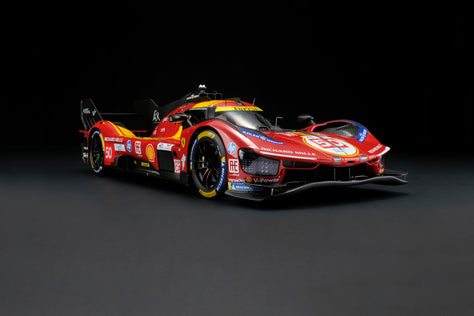 A red and yellow Ferrari 499P 2025 Le Mans racing car at 1.8 scale with multiple sponsors, displayed on a dark surface against a black background.