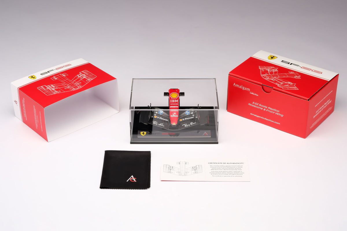 A miniature model of a red and black Formula 1 Ferrari SF-26 nosecone, mounted on a black display base inside a acrylic display box, against a neutral grey studio background.