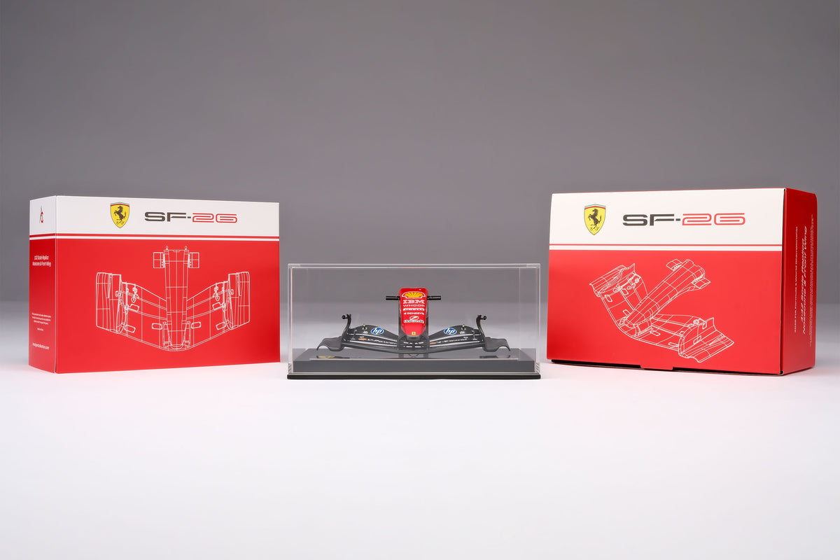 A miniature model of a red and black Formula 1 Ferrari SF-26 nosecone, mounted on a black display base inside a acrylic display box, against a neutral grey studio background.