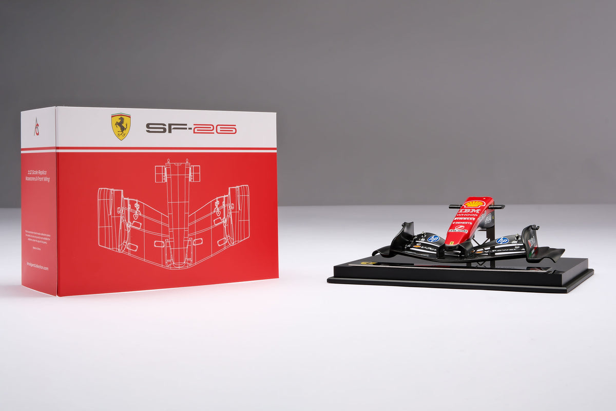 A miniature model of a red and black Formula 1 Ferrari SF-26 nosecone, mounted on a black display base surrounded by packaging, against a neutral grey studio background.
