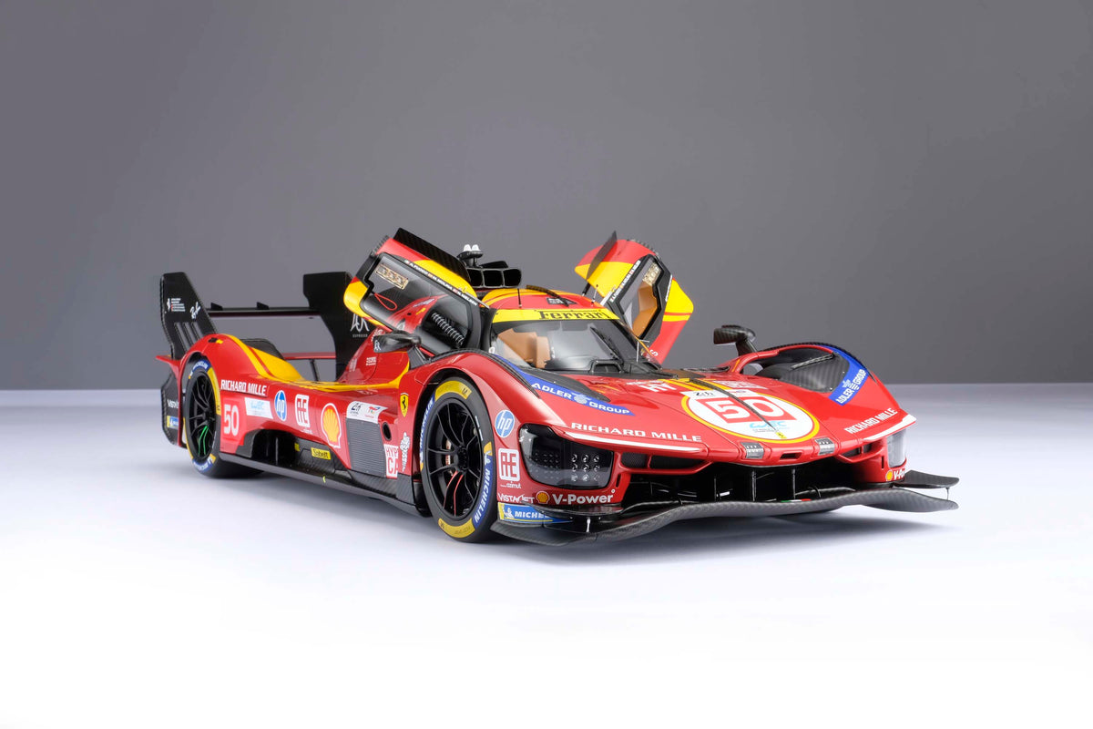 A red and yellow Ferrari 499P 2025 Le Mans racing car at 1.8 scale showing the opening doors feature on the model, displayed on a light surface.