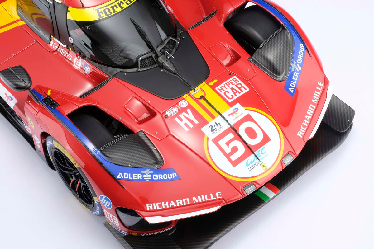 A detail shot of a  red and yellow Ferrari 499P 2025 Le Mans racing car at 1.8 scale with multiple sponsors, displayed on a light surface.