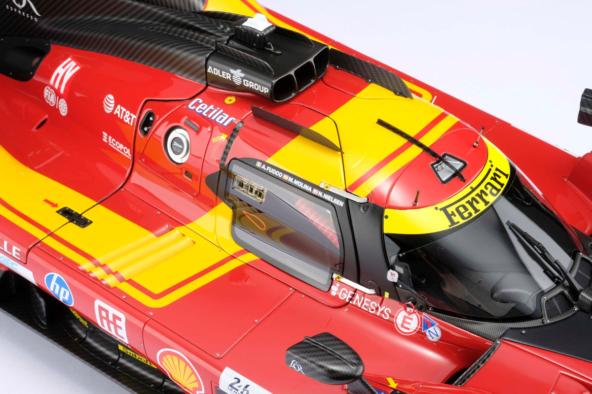 A detail shot of a  red and yellow Ferrari 499P 2025 Le Mans racing car at 1.8 scale with multiple sponsors, displayed on a light surface.