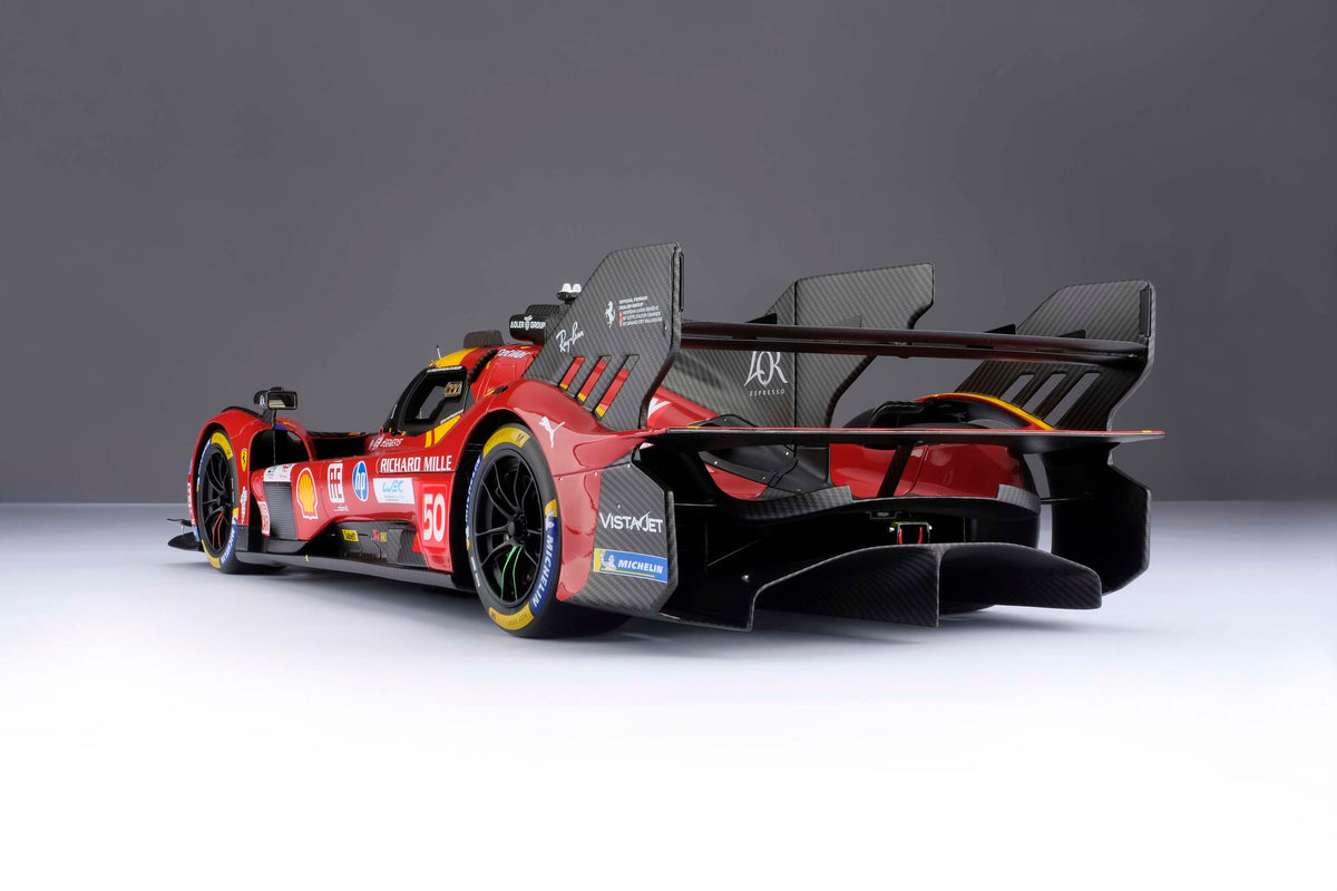 A red and yellow Ferrari 499P 2025 Le Mans racing car at 1.8 scale with multiple sponsors, displayed on a light surface.