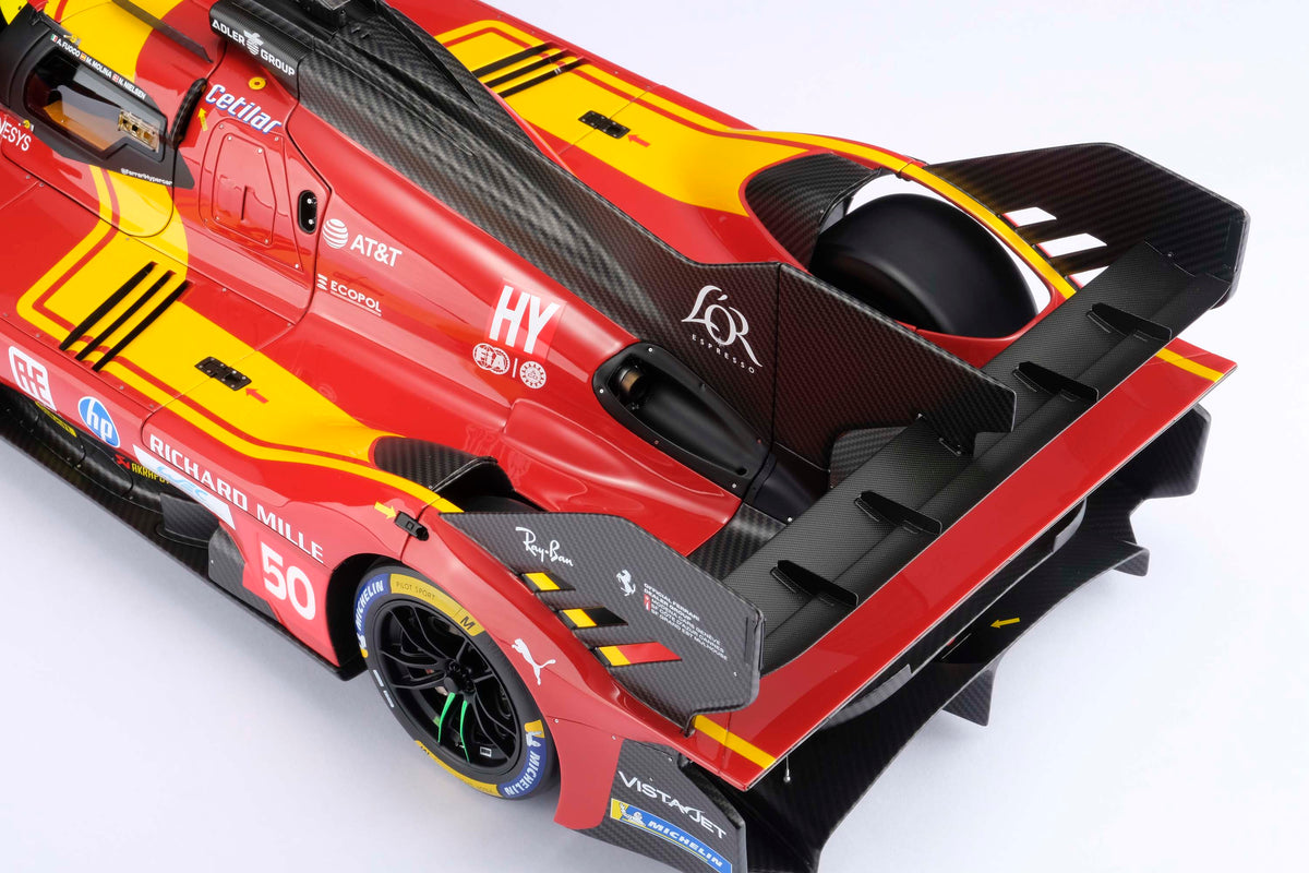 A detail shot of a  red and yellow Ferrari 499P 2025 Le Mans racing car at 1.8 scale with multiple sponsors, displayed on a light surface.