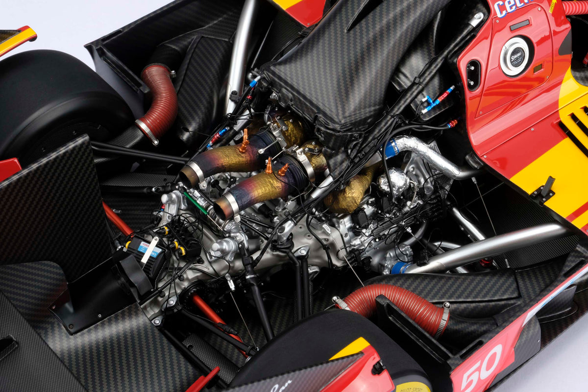 Close-up of a red and yellow Ferrari 499P cockpit interior, showing the intricate engine details