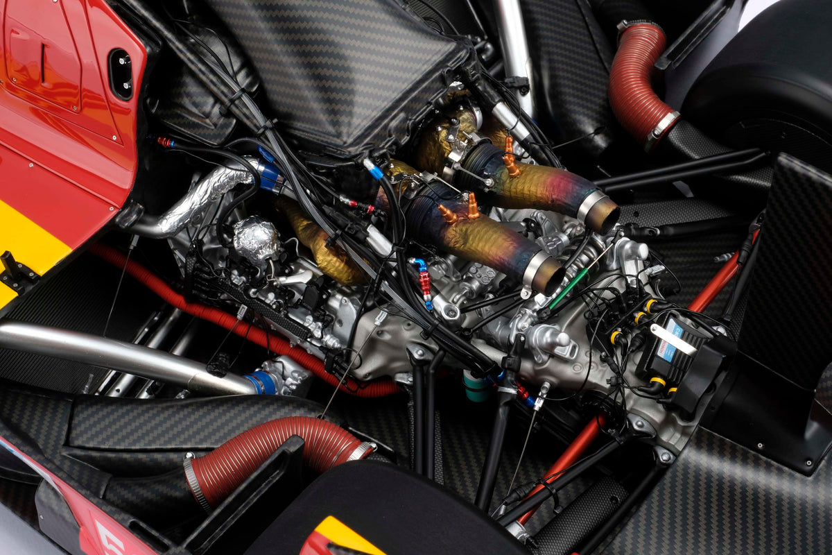 Close-up of a red and yellow Ferrari 499P cockpit interior, showing the intricate engine details
