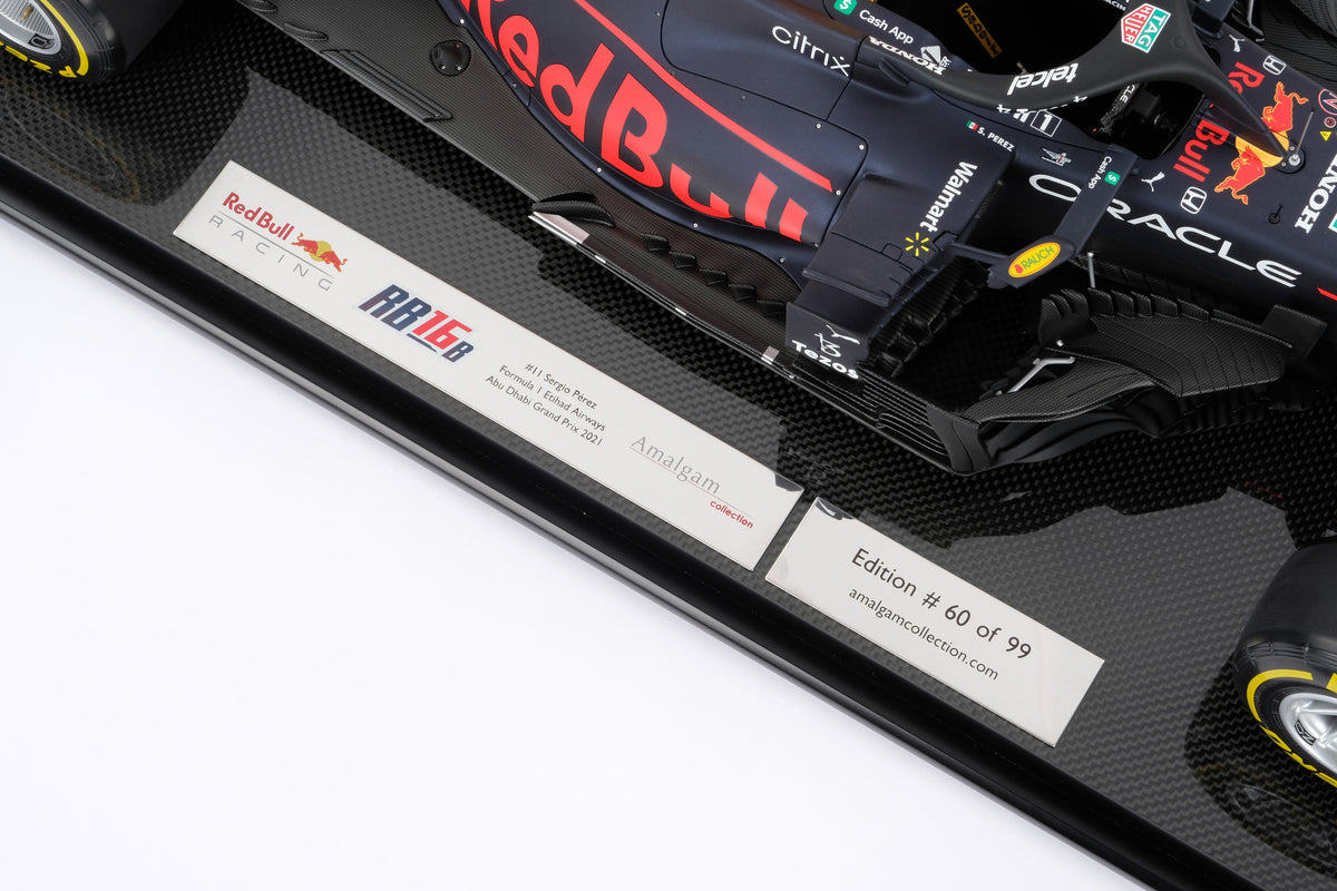 A detail close up of a 1:8 scale model of Sergio Perez's Red Bull Racing Honda RB16B on a display base showcasing the plaque, against a neutral background.